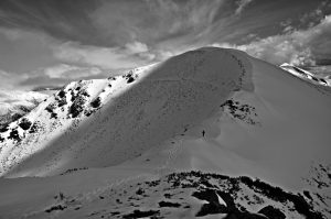Caminando por la cresta nevada de una montaña cerca del Puerto de Ancares, puerto de montaña de la sierra de Ancares que une la provincia de Lugo, con la provincia de León, a través de su municipio de Valle de Ancares, Ancares, El Bierzo, León, Castilla y León, España.