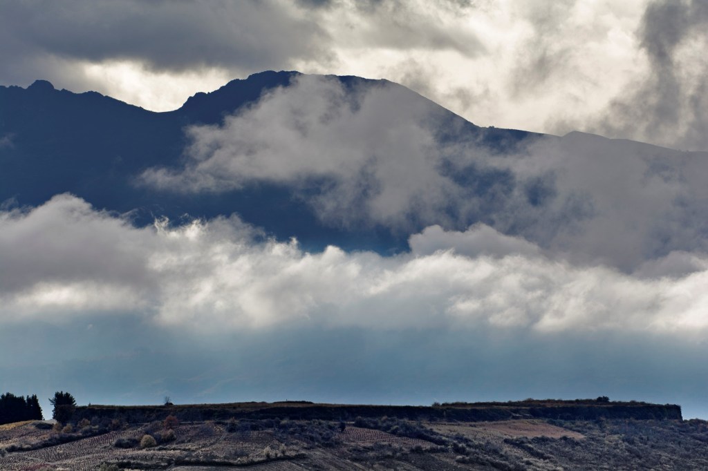 La meseta de Castroventosa besando las nubes desde una vista desde la carretera que va a Pobladura de Somoza, de la vertiente de Pieros, Cacabelos, El Bierzo, León, Castilla y León, España.