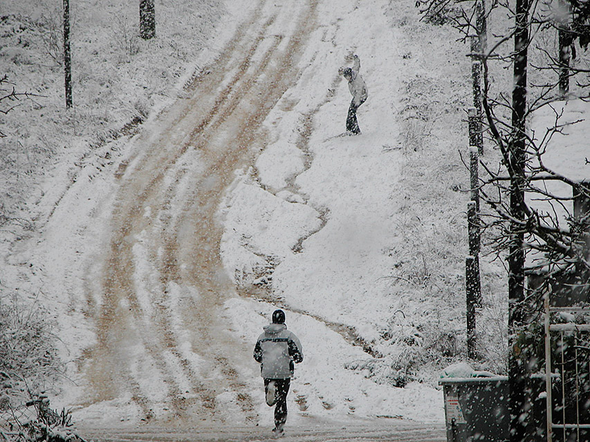 Dos entrañables adolescentes jugando con la nieve caída sobre la cuesta que sube al Campo de San Bartolo en Cacabelos, El Bierzo, León, Castilla y León, España.